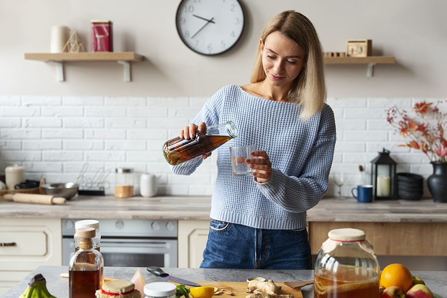 Een vrouw voegt C60-olie toe aan een smoothie in een keuken.